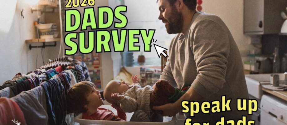 Picture of a father caring for two young children in a kitchen. One older child is sitting in a laundry basket whilst the father places the younger child, a baby, in the basket next to him. Laundry can be seen drying in the background. There is accompanying text which says '2026 Dads Survey' and 'speak up for dads'